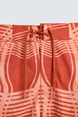 Short de baño color ladrillo con estampado de líneas curvas en color salmón. Tiene cintura elástica ajustable con cordón, bolsillos laterales y trasero.