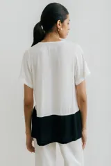 Remera blanca con corte horizontal y parte inferior negra. Cuello en V y mangas cortas.