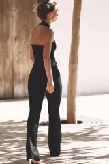 Pantalón negro de tiro medio, confeccionado en tejido elástico con cintura elastizada y corte acampanado.