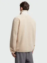 Buzo de tejido tipo teddy en color beige, con cierre frontal completo, cuello alto y un bolsillo de parche en el pecho con solapa y el logotipo de Moncler. Presenta bolsillos laterales con ribete y un diseño de corte holgado.