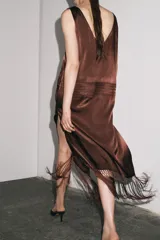 Vestido midi marrón con bordados florales y geométricos en el frente, escote redondo, mangas sisa, tejido plisado y flecos en el ruedo.