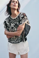 Top de Zara Woman Collection, color negro con apliques de crochet en color crudo. Cuello redondo y manga corta caída. Cierre en la espalda con abertura y botón.