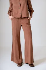 Pantalón de lino color beige, corte flare, tiro medio y costuras verticales al frente.