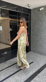 Vestido largo estampado con escote en V profundo y tirantes anchos. El diseño presenta un frunce o nudo en el centro del busto y tajos laterales en la falda.