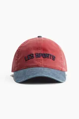 Gorra de sarga de algodón color rojo con visera azul y bordado frontal con la frase "Les Sports". Cuenta con cinta antitranspirante y hebilla metálica ajustable en la parte trasera.