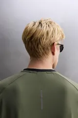 Camiseta deportiva verde militar confeccionada en tejido estructurado, ligero y elástico. Tiene cuello redondo, manga corta y bajo con aberturas laterales. Incluye logo estampado en el bajo.