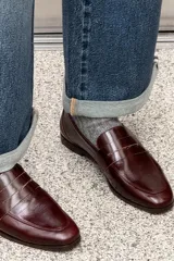 Zapato tipo mocasín de cuero color bordó, con detalle de antifaz y pespuntes en contraste.