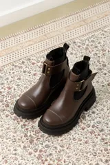 Botas de cuero color marrón oscuro, estilo Chelsea, con elástico lateral negro y suela track negra. Incluye correa de cuero desmontable con hebilla.