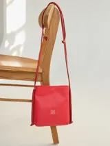 Cartera bandolera roja de cuero con logo grabado en el frente.