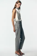 Pantalón de jean azul de tiro alto, corte mom fit, tobillero y con cinco bolsillos. Cierre frontal con cremallera y botón.