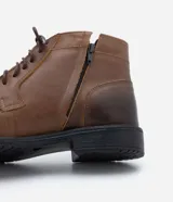 Bota de cuero marrón con caña corta, cierre de cordón y suela negra.