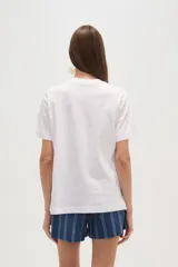 Remera blanca de algodón con cuello redondo y mangas cortas. Estampado frontal con diseño de peces azules sobre fondo a cuadros amarillos y texto "Isola di Capri" y "Amalfi Coast".