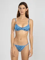 Bombacha de bikini azul con estampado animal print, cobertura mínima y tiras laterales ajustables.