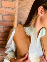 Camisa verde agua con cuello babero de puntilla blanca, mangas largas abullonadas con puños elastizados y cierre frontal con botones.