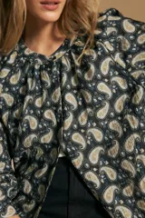 Camisa de manga larga con cuello mao y estampado paisley en tonos beige, marrón y azul sobre fondo claro. Presenta un calce holgado y puños ajustados.