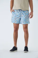 Short de baño azul con estampado de hojas y flores en blanco. Tiene cintura elástica con cordón ajustable, dos bolsillos laterales y uno trasero.