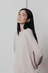 Sweater color crema de tejido de punto con hilos metalizados, corte relajado, hombros caídos y terminaciones clásicas.