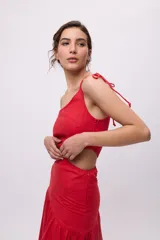 Vestido largo rojo de algodón y lino, con un hombro descubierto, bretel fino con lazo, recorte en la cintura y falda asimétrica con volados.