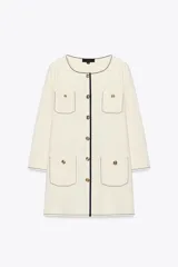 Chaqueta color crema de punto con cuello redondo y manga larga. Tiene bolsillos delanteros de plastrón, pespuntes combinados a contraste y cierre frontal con botones dorados.