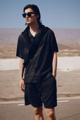 Camisa negra de manga corta en mezcla de algodón y lino. Modelo con cuello abierto, tapeta lisa y bolsillo superior abierto.
