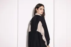 Campera deportiva negra y beige con cierre frontal, cuello alto, puños ajustados y ruedo regulable.