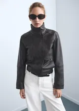 Pantalón de jeans blanco, tiro alto, corte wideleg (pierna ancha) y largo. Presenta bolsillos de parche en la parte delantera y bolsillos traseros.