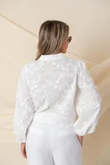 Camisa/chaqueta blanca de algodón con bordado floral en hilo de seda al tono, manga ancha terminada en frunce y botones forrados.