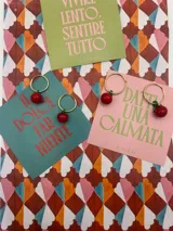 Par de aros dorados con dije colgante de cereza roja.