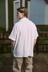 Camisa blanca de popelina con cuello resort, mangas cortas y cierre frontal con botones.