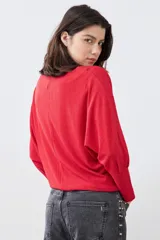 Blusa roja de tejido de punto acanalado, con escote barco y mangas dolman largas.