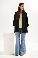 Sobrecamisa beige de corte recto, cuello mao y mangas 3/4. Presenta cierre frontal con botones de madera y bolsillos laterales.