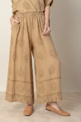 Pantalón palazzo de lino color beige con estampado floral al tono, cintura alta con elástico y corte ancho.