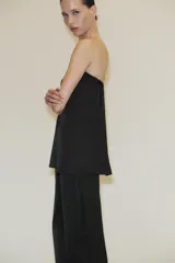 Top bandeau negro de tejido satinado con escote recto y hombros descubiertos. Tiene bandeau interior y cierre lateral con cremallera oculta.