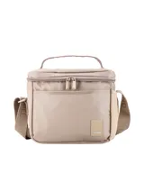 Set de tres piezas de accesorios de nylon color beige claro, compuesto por una mochila con bolsillo frontal, una lonchera con asa superior y una cartuchera pequeña con cierre. Todos los artículos tienen un diseño minimalista y liso, con una pequeña etiqueta de cuero sintético con el nombre de la marca.