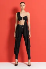 Conjunto negro de top con un solo tirante y detalle de cadena plateada, con pantalón ajustado con aberturas en los laterales y cadena plateada en la cintura.