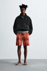 Short de baño color ladrillo con estampado de líneas curvas en color salmón. Tiene cintura elástica ajustable con cordón, bolsillos laterales y trasero.