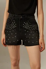 Short de jean negro con tachas plateadas en la parte delantera y ruedo desflecado.
