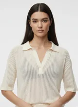 Remera oversize con cuello tipo polo y mangas cortas con hombros caídos, color crema.