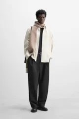 Camisa color crema de corte relaxed fit, confeccionada en tejido de mezcla de algodón suave al tacto. Tiene cuello solapa, manga larga con puños abotonados, un bolsillo de parche en el pecho y cierre frontal con botones.