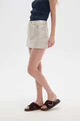 Falda mini color beige, de jean rígido, con bolsillos delanteros y traseros.