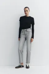 Pantalón de jean gris de tiro alto, corte mom fit, con trabillas y cinco bolsillos. Cierre frontal con cremallera y botón metálico.