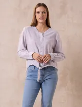 Blusa de algodón a rayas verticales finas en tonos lila y blanco, marca Dash. Escote en V y abertura frontal con botones. Mangas largas regulables con presilla y botón. Terminación de ruedo anudado.