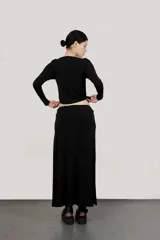 Falda larga negra con tajo lateral y pretina con trenza de terciopelo.