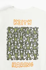 Remera blanca de algodón de corte holgado con estampado del artista Keith Haring en el pecho. Modelo de H&M con cuello redondo y mangas cortas.