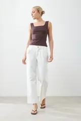 Pantalón wide leg color crudo con pinzas delanteras y cierre con botón y cremallera.