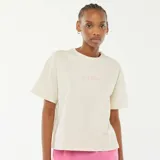 Remera color crema de corte holgado, con cuello redondo y estampado con la frase "San Diego" en color rosa.
