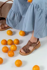 Sandalias de cuero color marrón con tiras anchas, hebilla lateral y suela track.