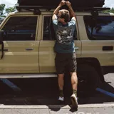 Remera verde con estampado de un sol sonriente y el texto "Roark House of Darwin".