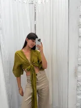 Top color verde oliva confeccionado en lino, con mangas 3/4 amplias y lazo versátil para atar al frente o atrás.