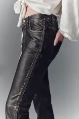 Pantalón jeanero de cuero ovino color marrón oscuro, de calce flare con efecto gastado y tachas aplicadas.